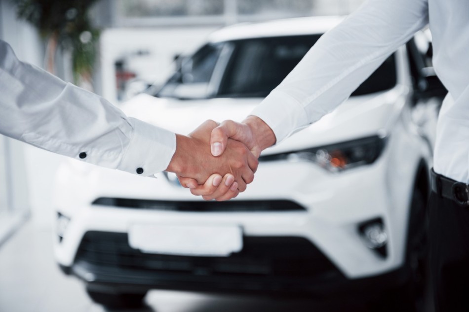 thumbnail close up of sales manager in black suit selling the car to the customer